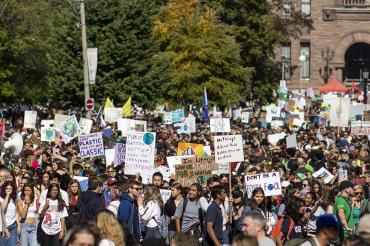 Protesters hold signs in front of Queen's Park during climate rally