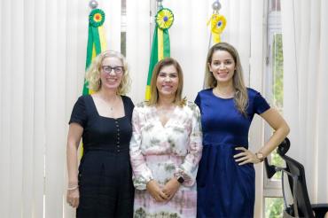 Denise Gastaldo, Margarida de Aquino Cunha and Rozilaine Redi Lago stand in front of flags