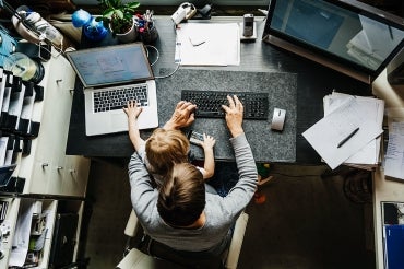 Mother with child on lap at her home office