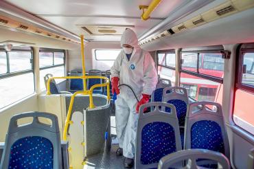 a person dressed in protective equipment sprays disinfectant on a bus in Macedonia