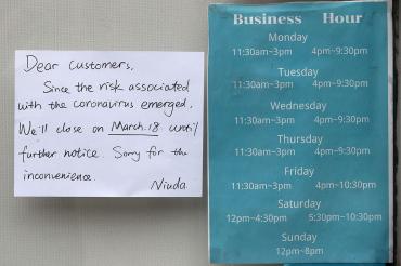 A sign reads: Dear customer, since the risk associated with the coronavirus emerged we'll close on march 18 until further notice. Sorry for the inconvenience. niuda