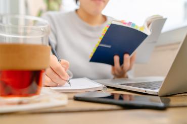 Asian female studying from a book and taking notes