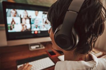 A person wears headphones while participating in a group video conference call