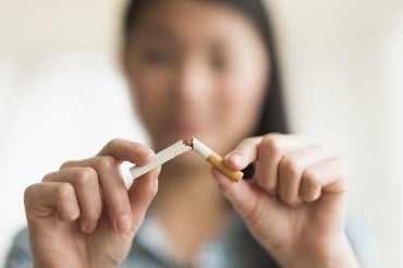 Asian woman breaking a cigarette in half