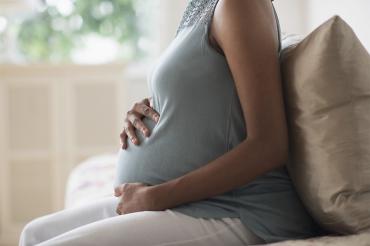 Black pregnant woman sitting on a sofa