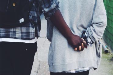 a young couple holds hands while walking down the street