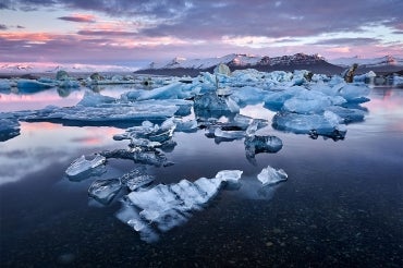 Sun sets over multiple small icebergs