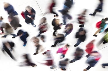 a bluryr overhead shot of a crowd of people moving about while on cell phones