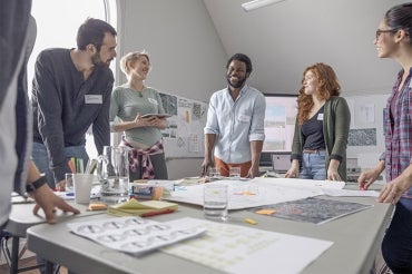 A group of smiling young workers gathered around a table having a meeting