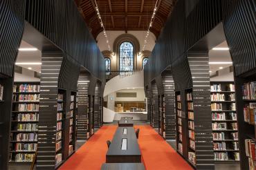 A view of the newly renovated library at University College with spiral staircase and stained glass window in the background