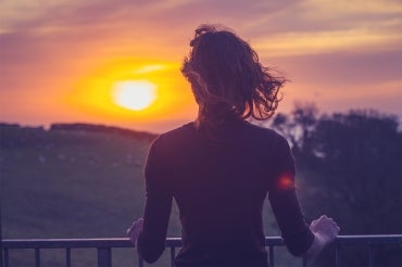 woman looks off into a sunset