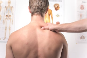 A teenager, with his back to the camera, receives treatment in a doctor's office