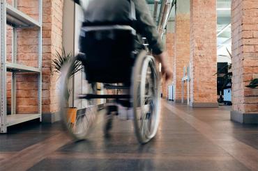 man in wheelchair moves across a room