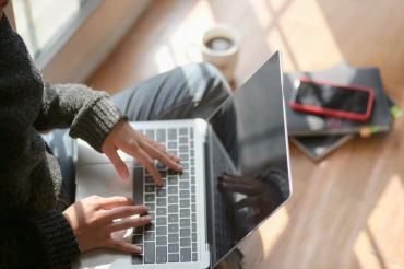 Photo of a person, shown from the neck down, typing on a keyboard