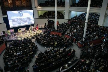 a wide view of the inside of a full convocation hall during the memorial