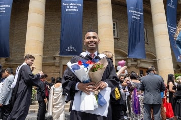 Jaivet Ealom stands in front of Convocation Hall after his graduation ceremony
