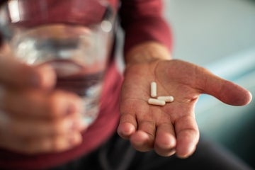 Man holding pills and a glass of water