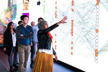 A woman gestures to diagram on a visualization screen.