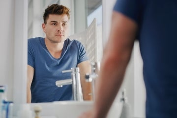 man looking at himself in a mirror and looks sad