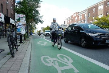 a woman rides her bike in a bike lane along Danforth Avenue in Toronto