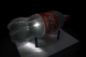 a video still showing a photon of light passing through a water-filled coke bottle