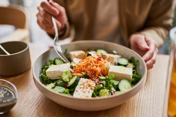 older asian woman eating a tofu salad