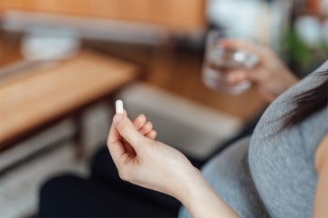 pregnant woman holding a folic acid supplement 