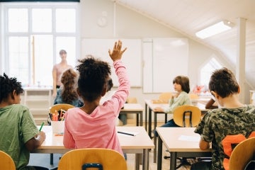 young female student raises her hand in a classroom