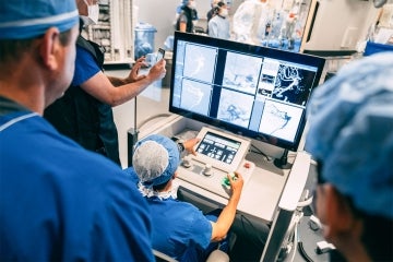 A surgeon at the controls of the robot conducting the procedure