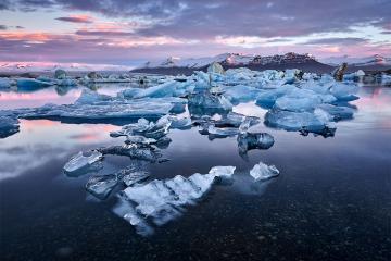 Sun sets over multiple small icebergs
