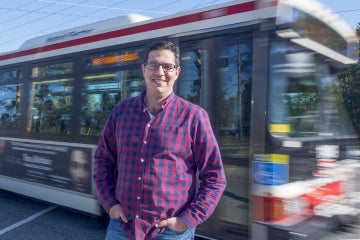 Steven Farber outside with a bus passing behind him