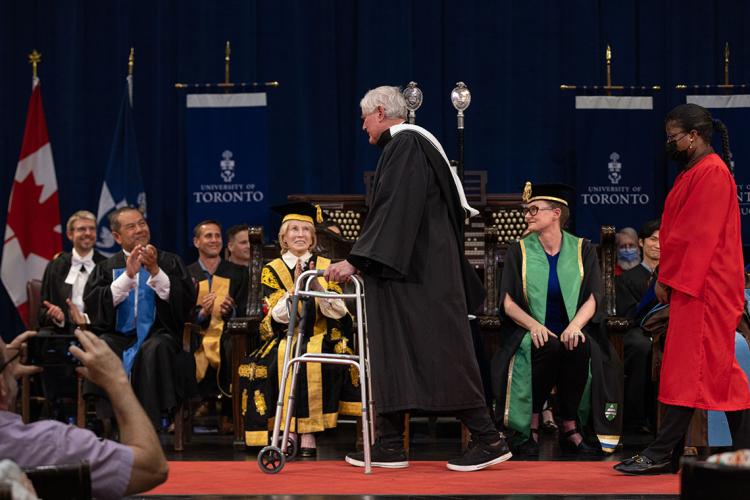 John Bond crosses the stage with is walker during convocation 