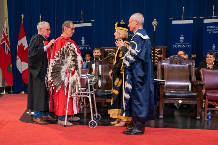 Wilton Littlechild is hooded by his friend Bruce Kidd during his honorary degree ceremony