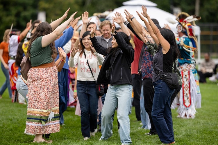 people raise their hands to form a tunnel while participants dance through it